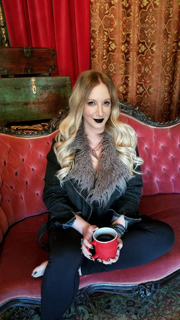 Woman sitting on a red couch holding a red mug with a dark background