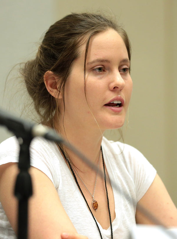Woman speaking into a microphone with a neutral background