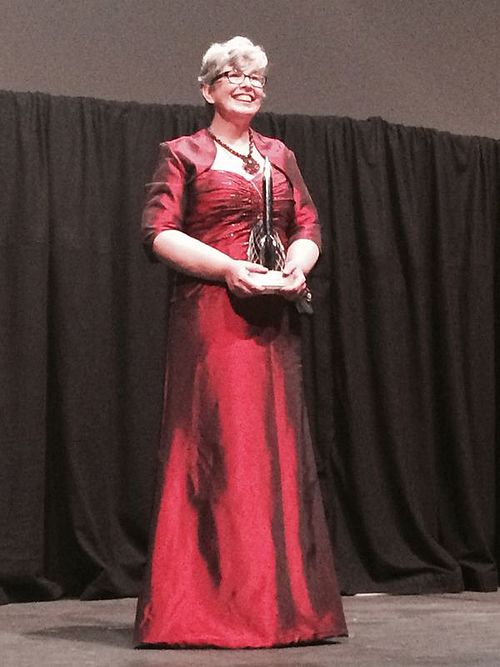 Woman in a red dress standing against a black curtain