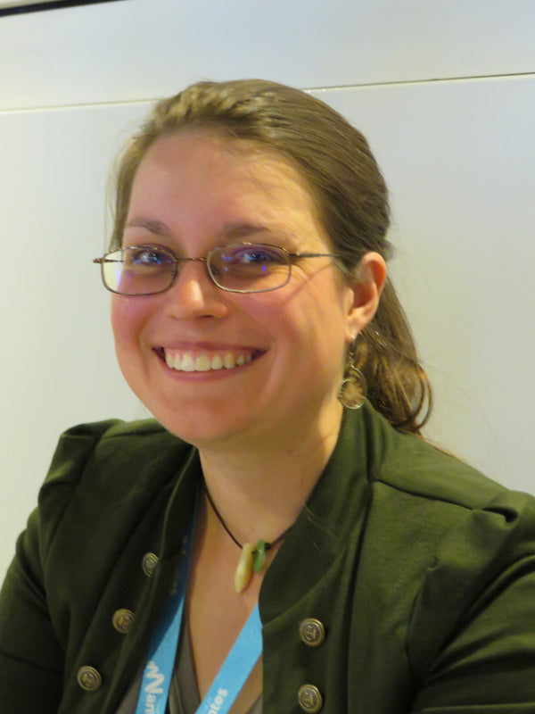Woman wearing glasses and a green jacket with a white background