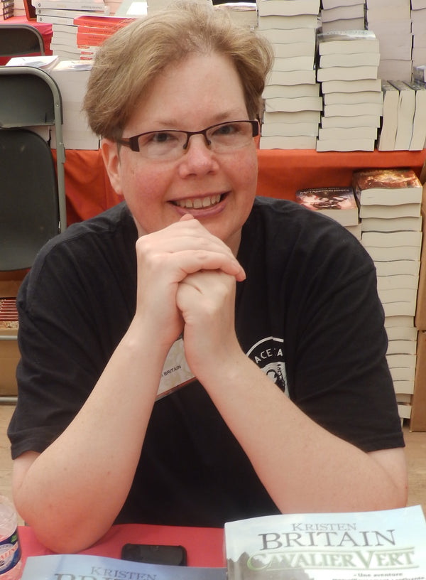 Person sitting in front of a bookshelf with books on a table