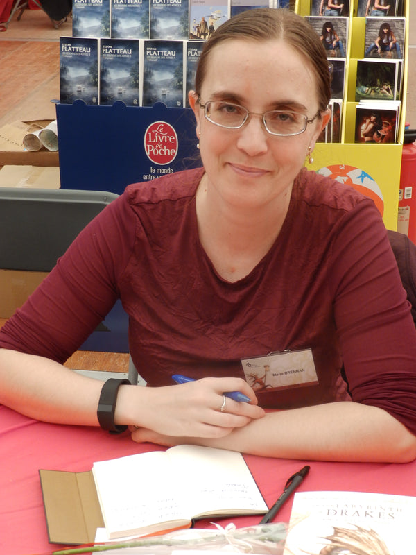 Woman sitting at a table with books and stationery in the background