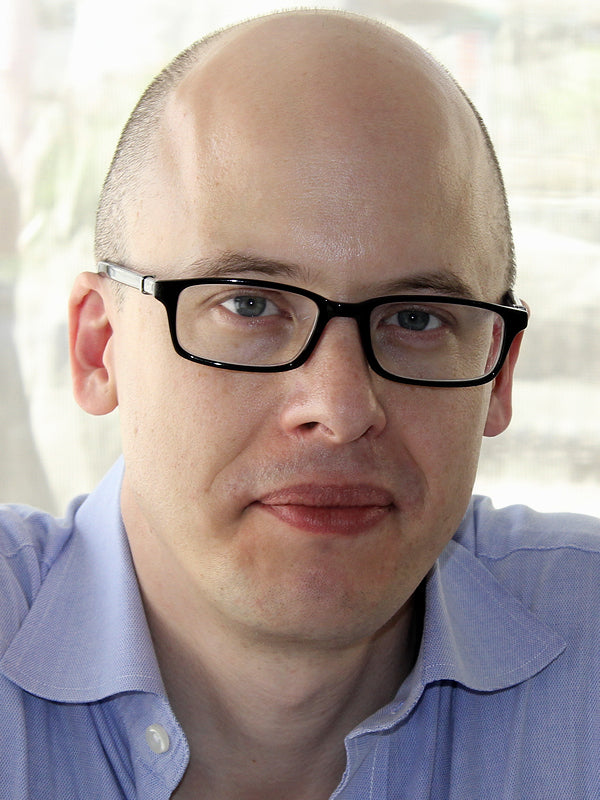 Man wearing glasses and a light blue shirt with a blurred background