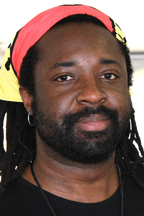 Man with dreadlocks and a colorful headband wearing a black shirt.