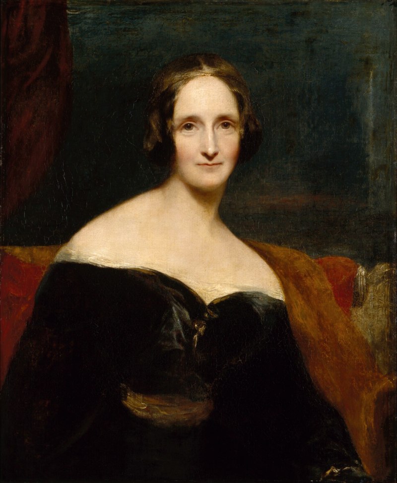 Portrait of a woman in a dark dress with a red couch and dark background