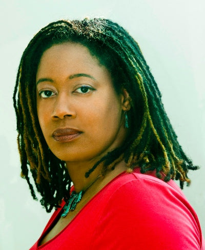 Woman with green braided hair wearing a red top against a light background