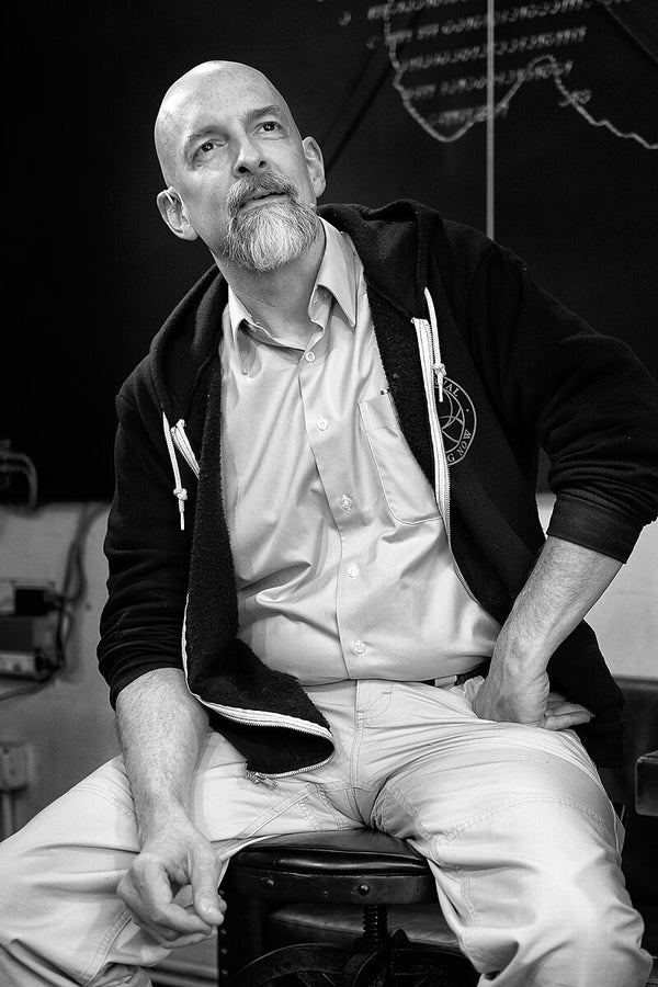 Man sitting on a stool in a room with musical instruments in the background