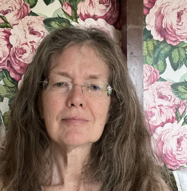 Woman with glasses in front of a floral wallpaper background