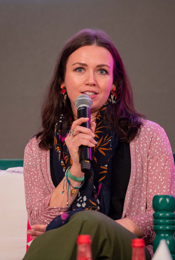 Woman speaking into a microphone at an event with a neutral background