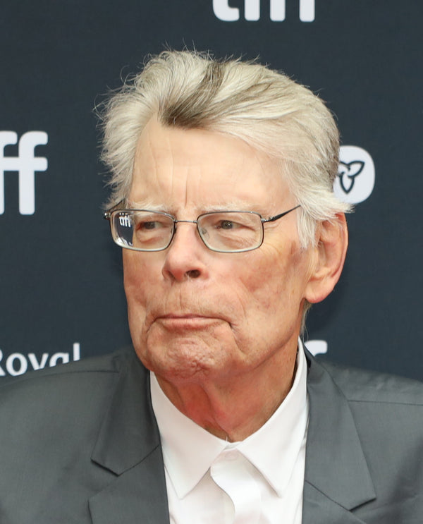 Man with glasses and gray hair wearing a suit at an event with visible branding.