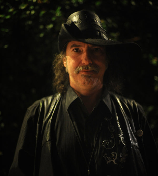 Man wearing a leather hat and jacket with a dark background