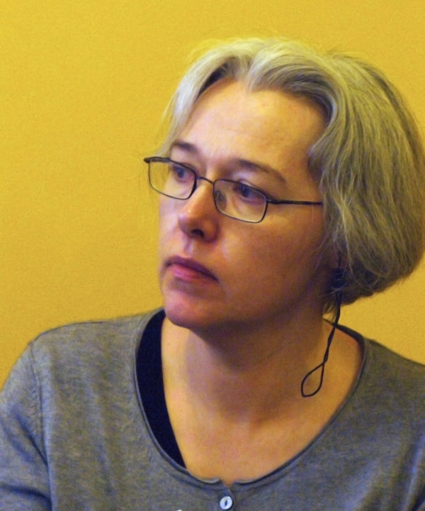 Person wearing glasses and a gray shirt against a yellow background